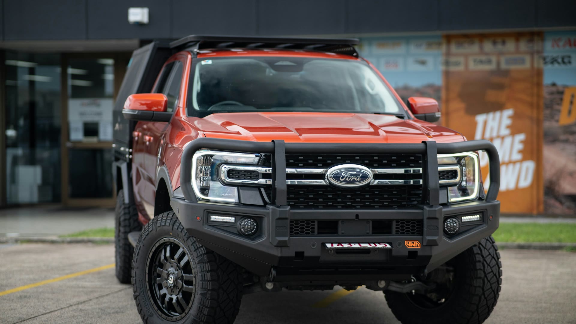 Car window tinting Cockburn: orange 4WD ute with a bull bar parked outside a building