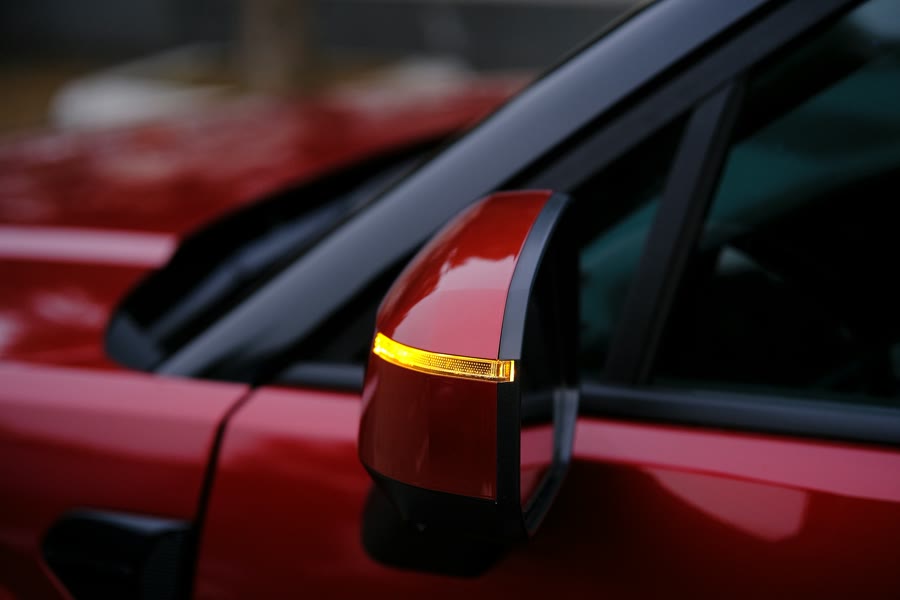 Tinting for glare: side mirror and window of a modern red car