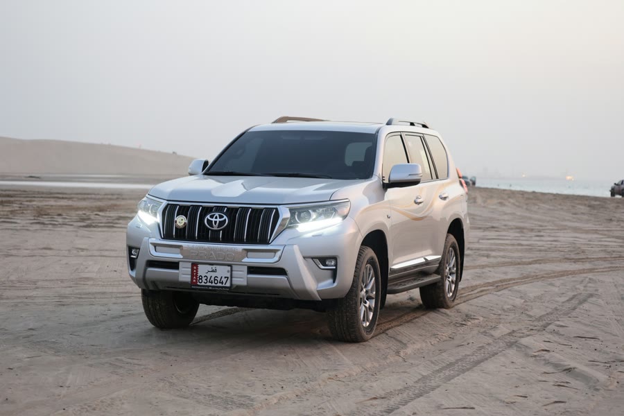 Coastal driving with window tint: a silver SUV parked on a sandy beach