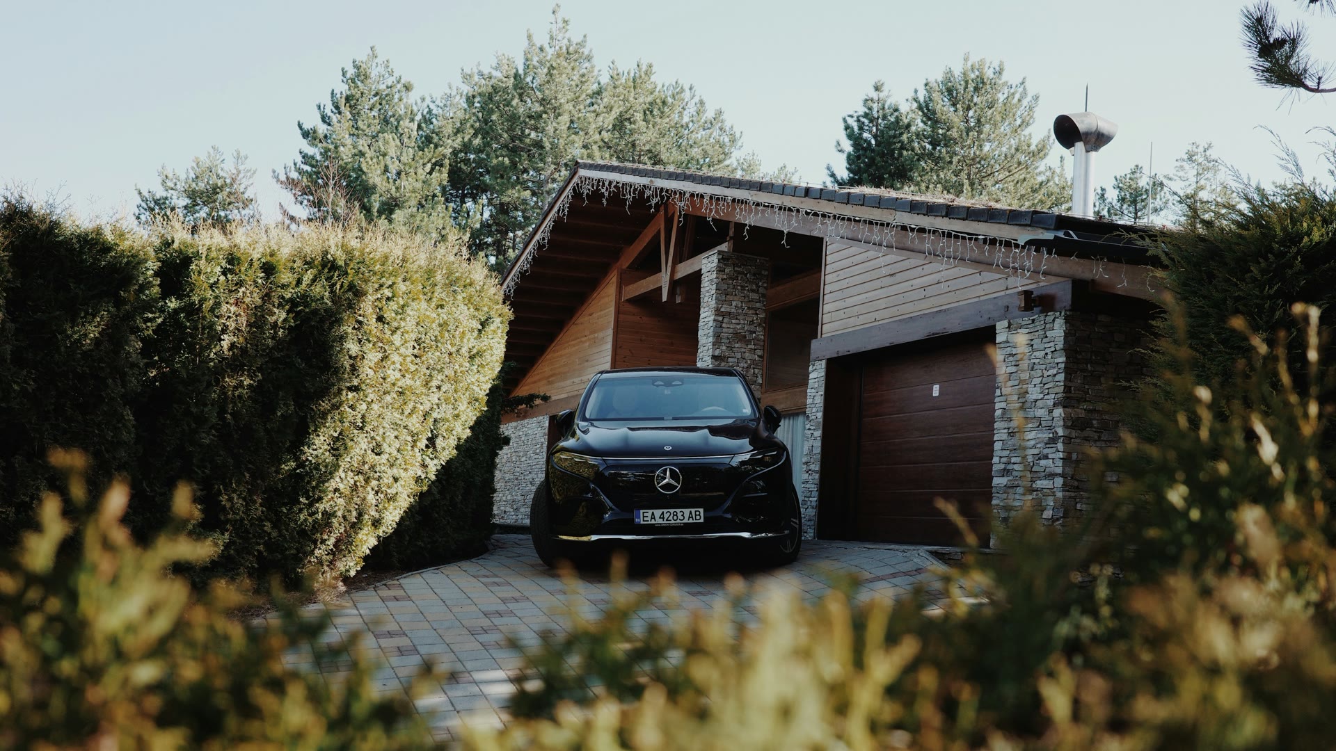 Car window tinting Wanneroo: a black car parked on a driveway in front of a garage