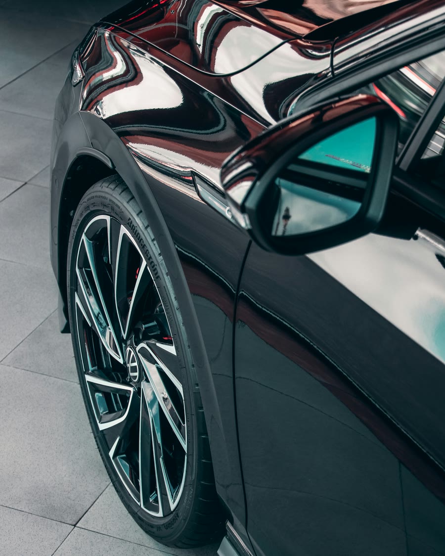 Ceramic coating finish: mirror-like reflections in the dark paint of a car door and wheel arch