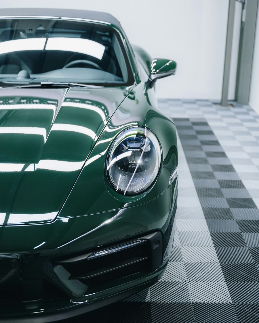 Ceramic coating aftercare: green sports car bonnet and headlight reflecting studio lights