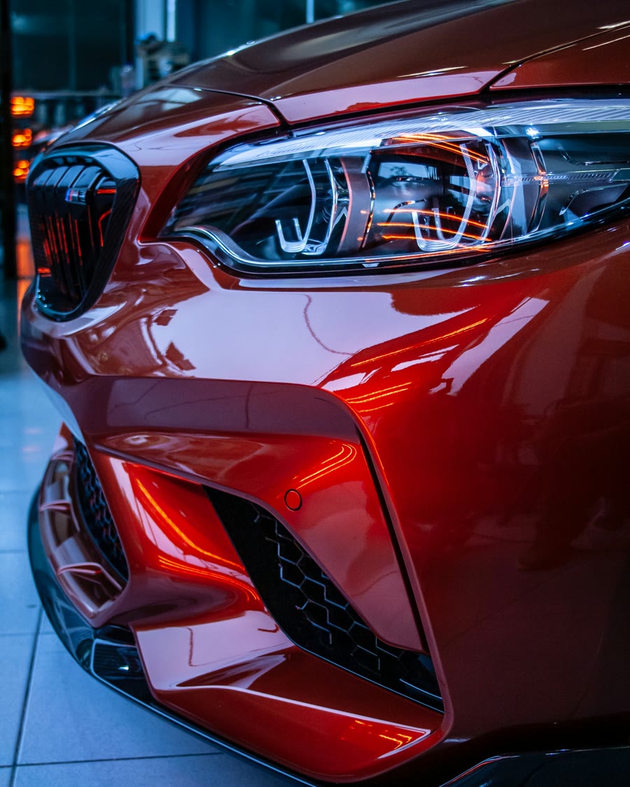 Ceramic coating gloss: deep red paint and LED headlight on the front of a sports car